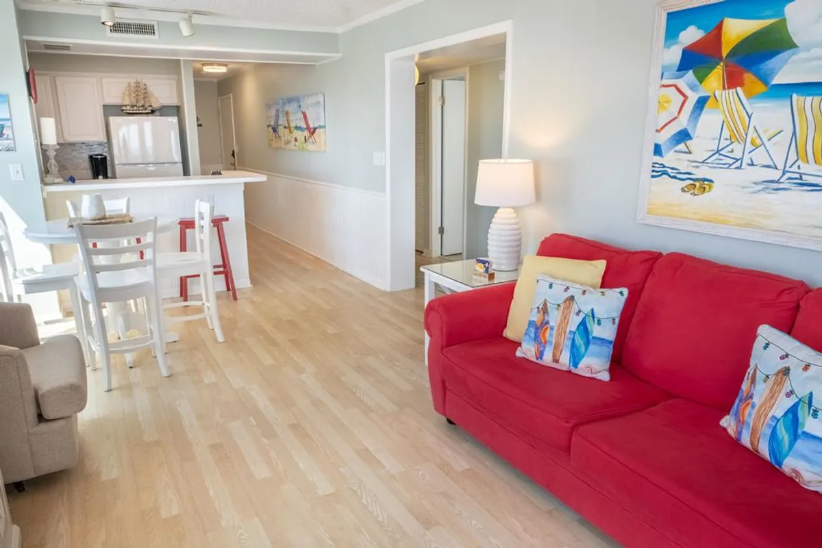 This image features the dining area adjacent to a red couch, complemented by colorful artwork and an inviting table setting. The design encourages socializing and shared meals, while the proximity to the living area supports the open-plan flow described in the section.
