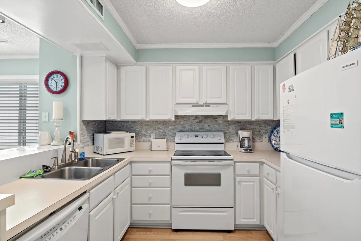A welcoming kitchen with white cabinetry, stainless steel appliances, a decorative backsplash, and a kitchen sink. The layout suggests a well-equipped space for extended stays, with plenty of room for cooking and socializing.