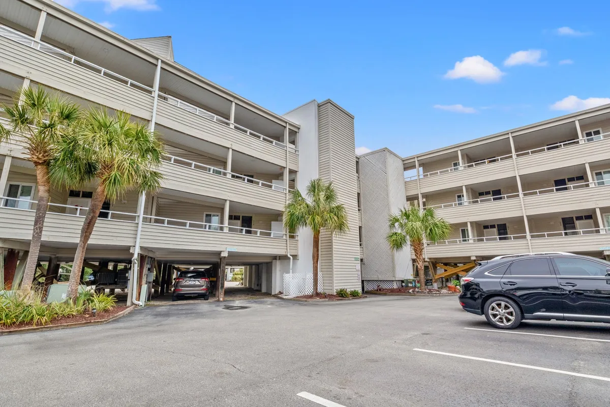 The exterior shot features palm trees, a multi-level parking structure, and several cars, creating a relaxed, sun-filled outdoor atmosphere. The scene suggests arrival, convenience, and the beginning of an adventure along the oceanfront.